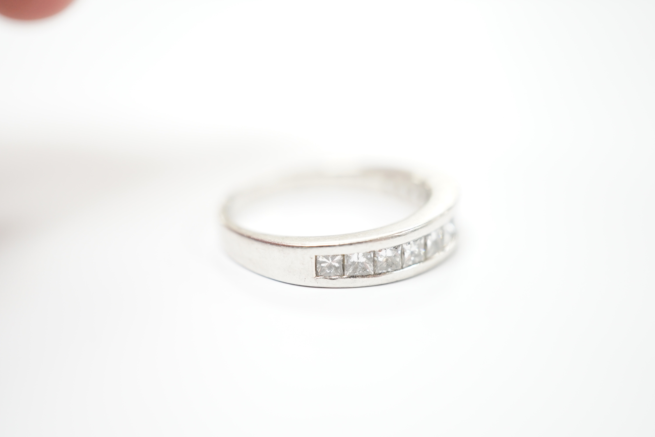 A white metal (engraved PT 950) and channel set twelve stone diamond half eternity ring, size N/O, gross weight 6.7 grams.